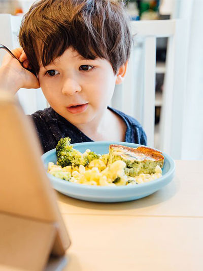 A child with a spoon in his mouth having toys around them
